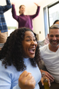 Excited diverse male and female friends watching sport on tv at home and drinking beers, copy space. Lifestyle, sport, competition, entertainment, friendship and domestic life, unaltered. Excited diverse male and female friends watching sport on tv at home and drinking beers, copy space. Lifestyle, sport, competition, entertainment, friendship and domestic life, unaltered.